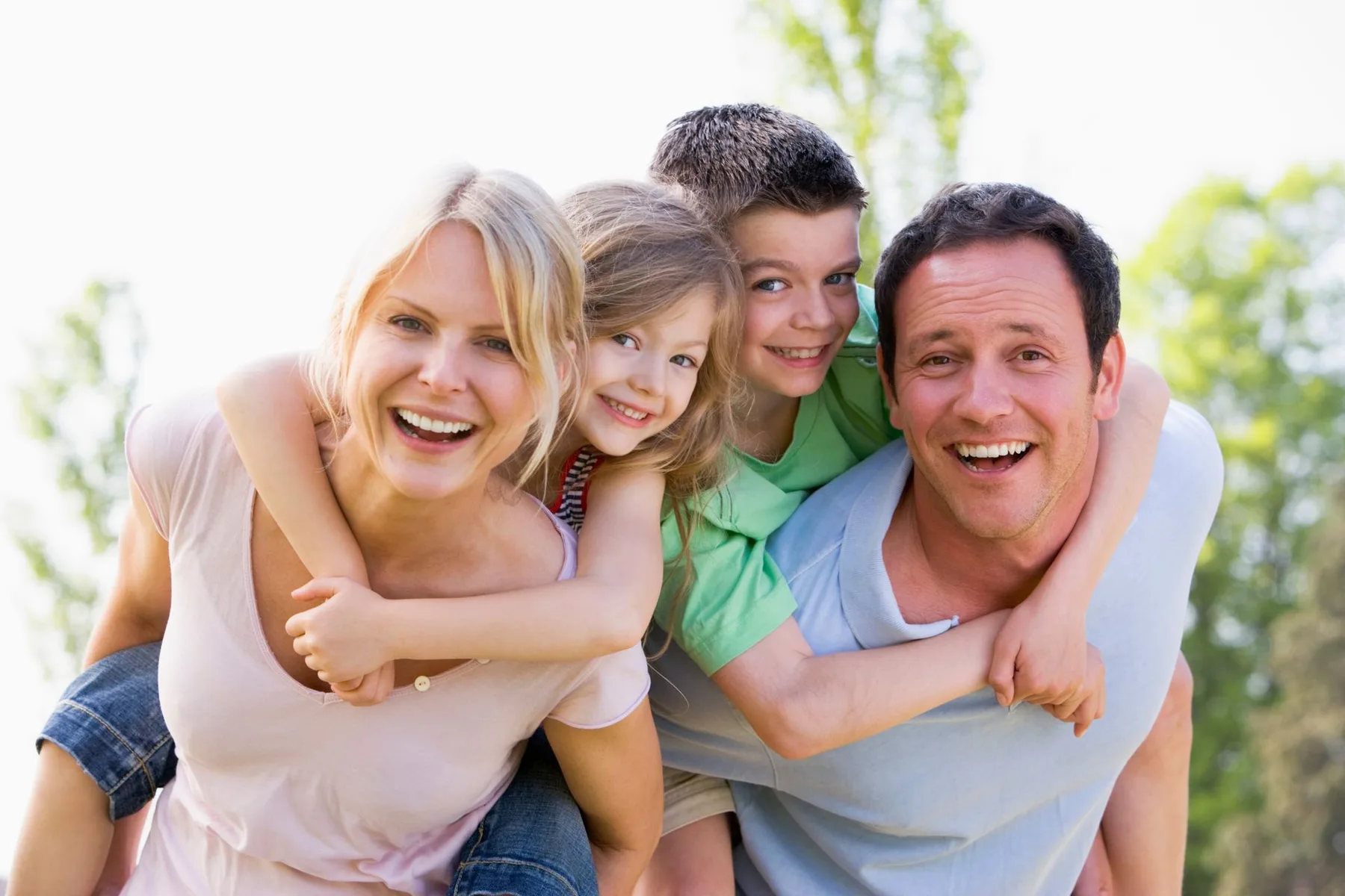 A mother, father and their two children laughing together outdoors